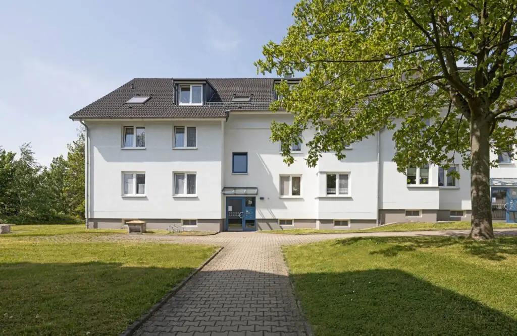 Weißes Mehrfamilienhaus mit Garten